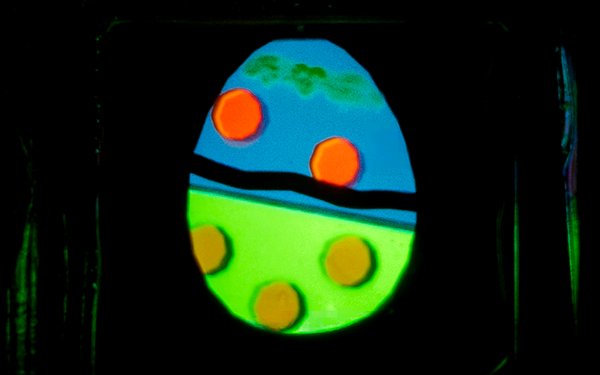 Das Bild zeigt ein Osterei aus verschieden farbigen organischen LEDs auf einer Glasplatte.