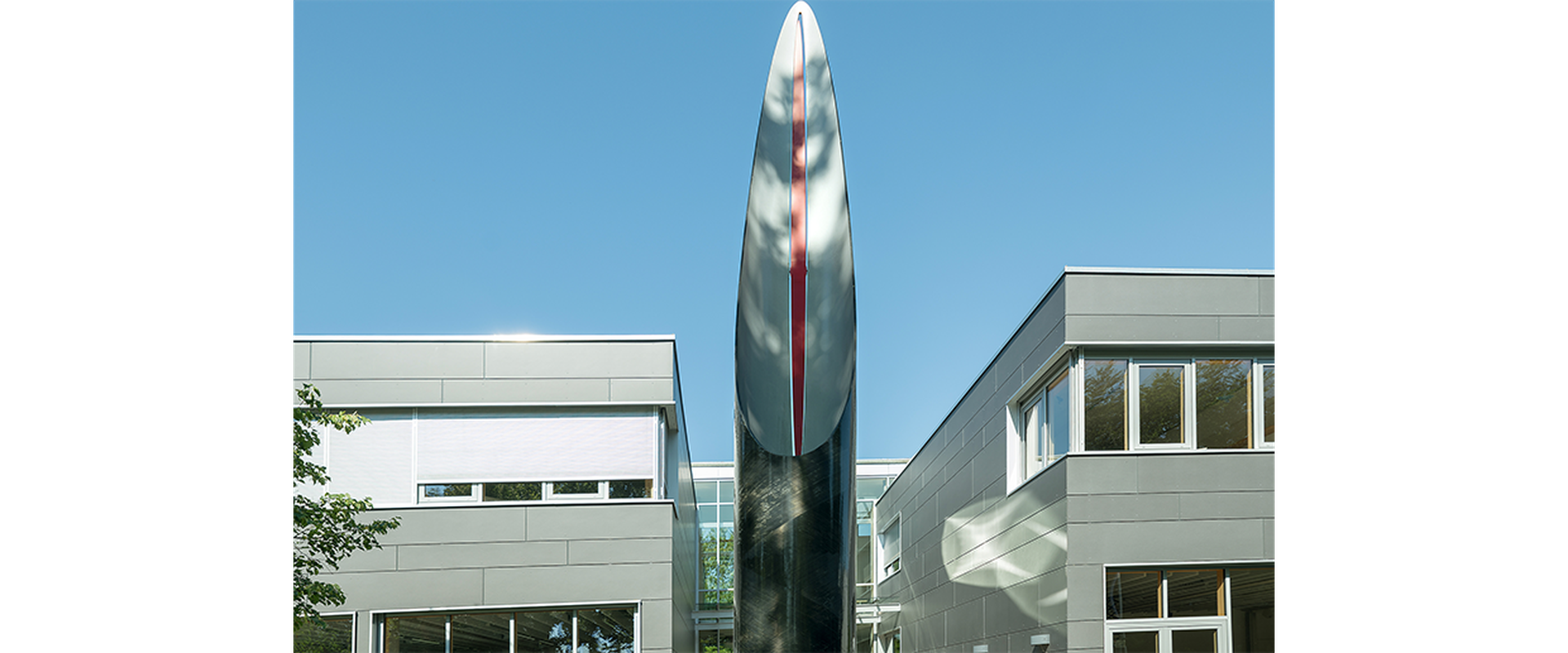 Auf dem Bild sieht man das Kunstwerk Pip vom Künstler Robert Kessler. Es stellt eine silberene Säule, die nach oben spitz zuläuft, dar.
