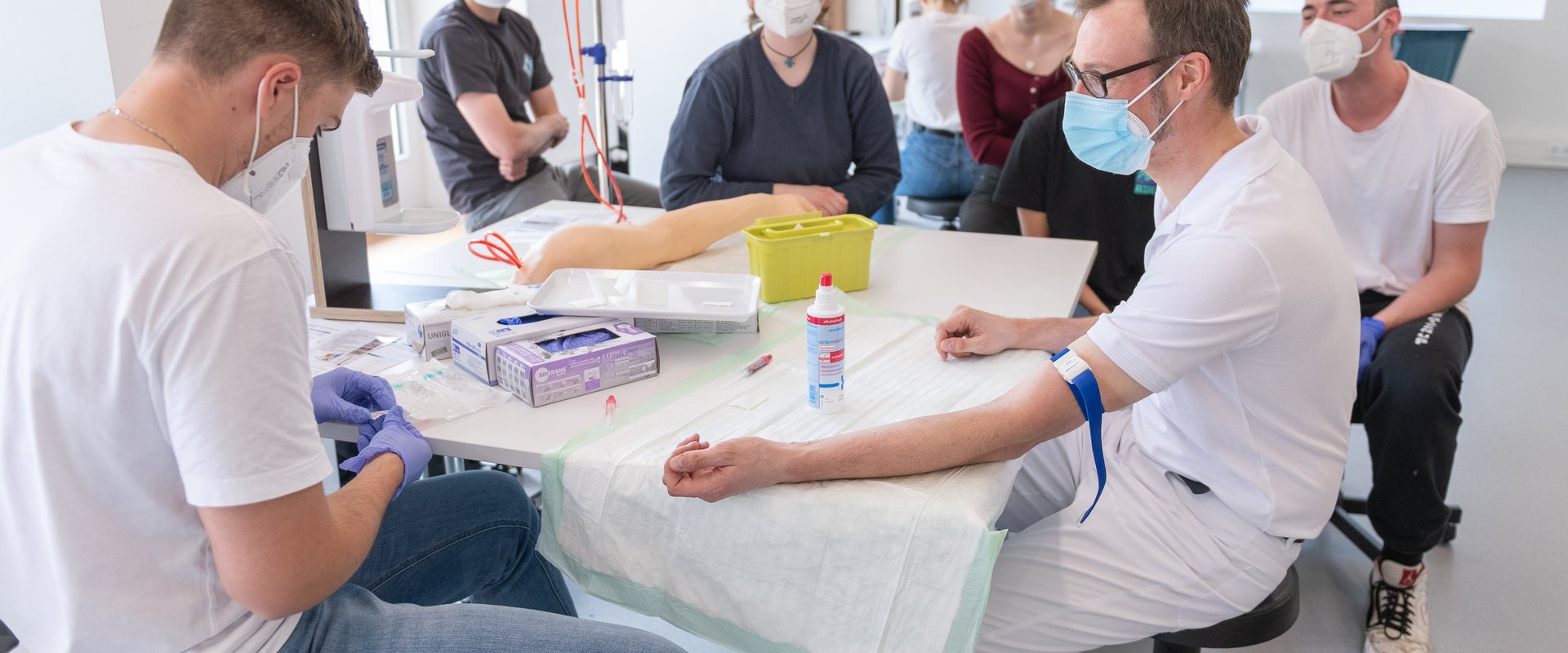 Medizinstudierende bei Blutabnahme am Dozenten