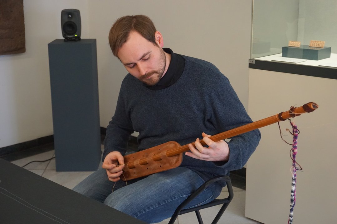 Exkursionsteilnehmer beim Ausprobieren eines rekonstruierten antiken Musikinstruments im Martin von Wagner Museum in Würzburg.