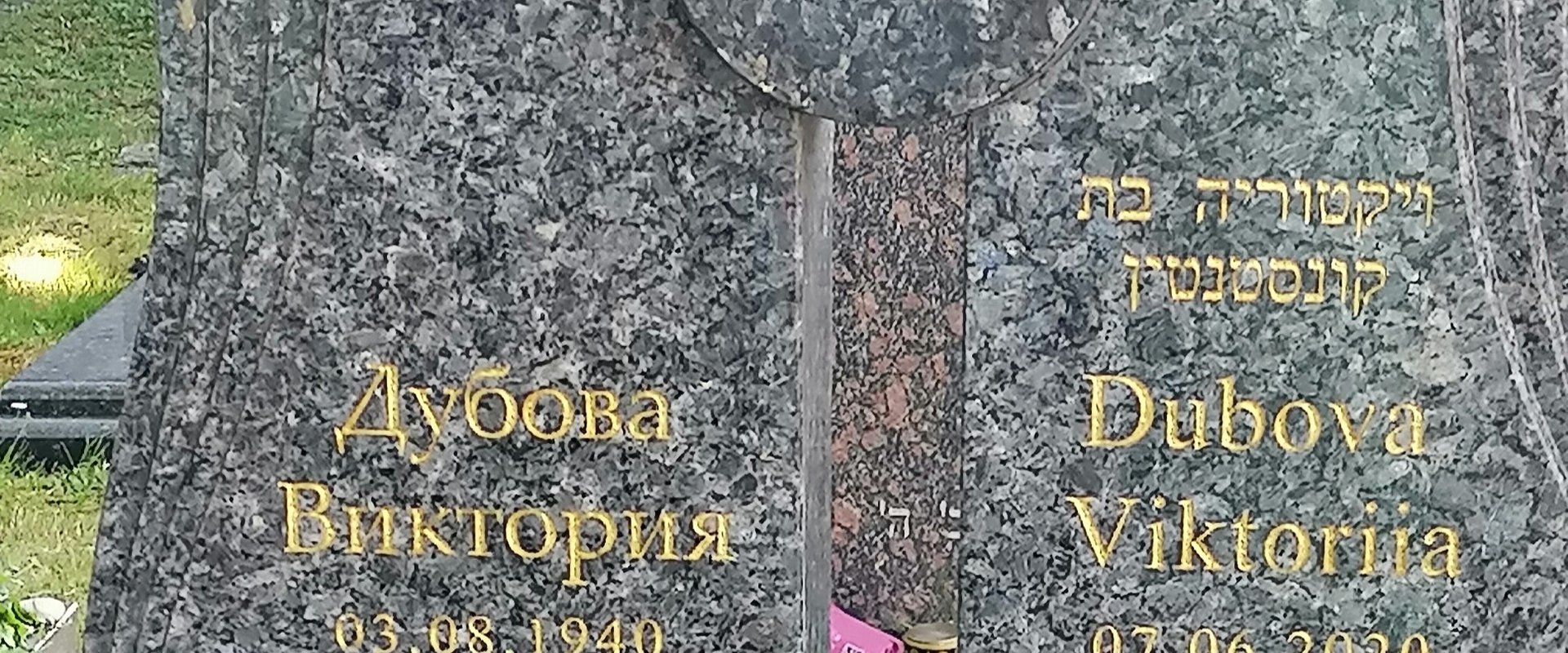 Auf dem Bild ist ein Grabstein mit dreisprachiger Inschrift zu sehen.