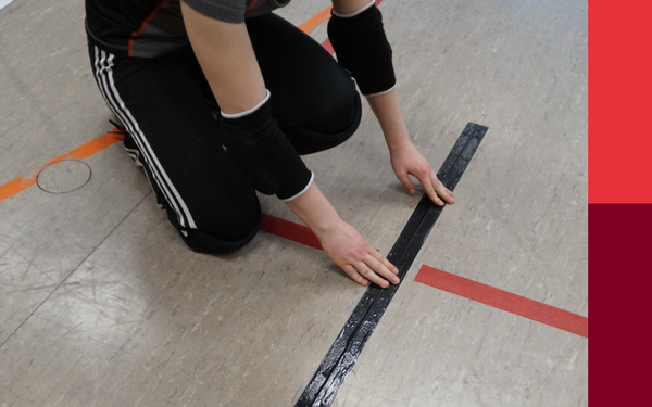 Person mit H?nden auf dem Hallenboden an einer Linie