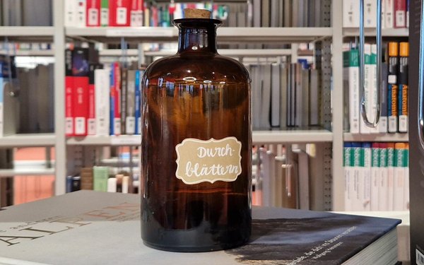 Braune gl?serne Apothekerflasche, die auf einem Buch steht