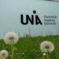Gras und Blumen mit Uni-Logo am Y-Gebäude