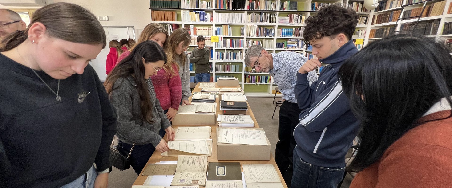 Es sind die Exkursionsteilnehmenden zu sehen, wie sie die ausgelegten Dokumente des Masaryk-Instituts betrachten.