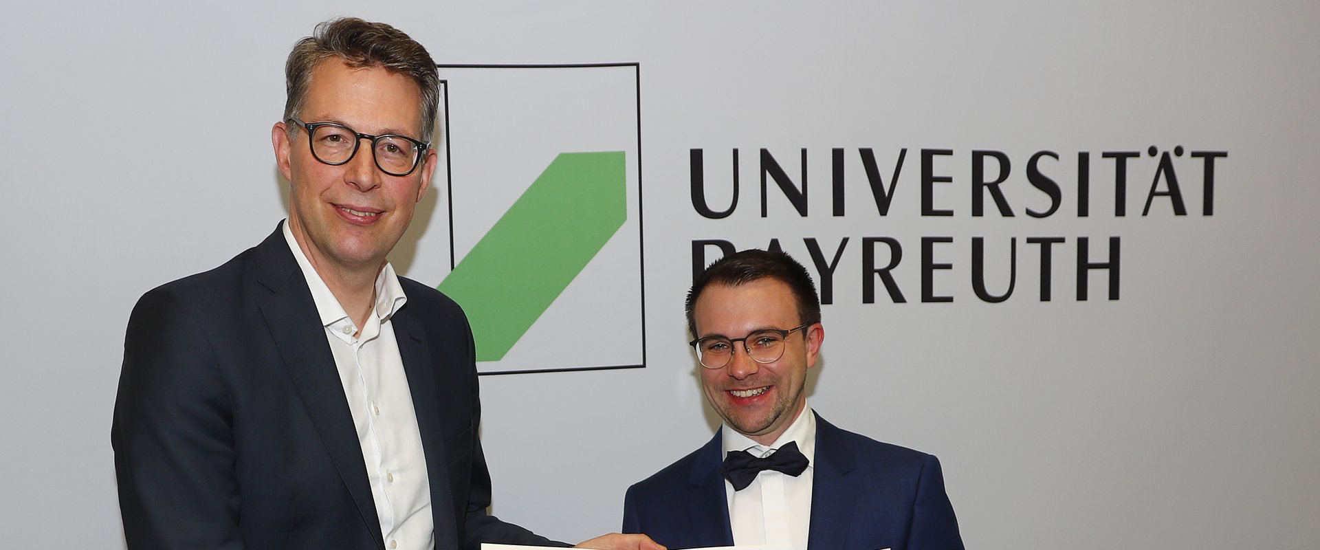Minister Markus Blume überreicht Dr. Sebastian Franz eine Urkunde (Staatspreis für gute Lehre 2021)
