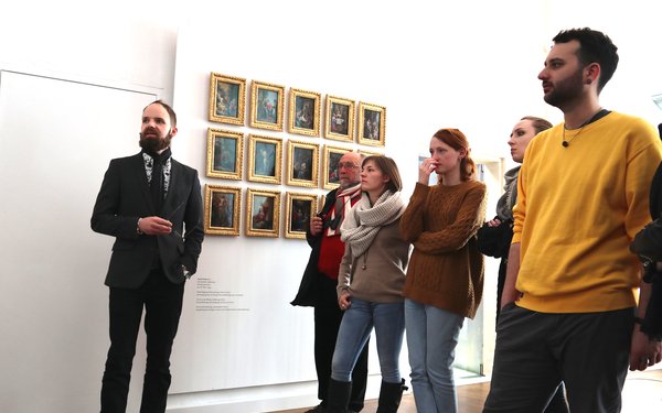 Studenten hören dem Vortrag eines Dozenten in einer Ausstellung zu
