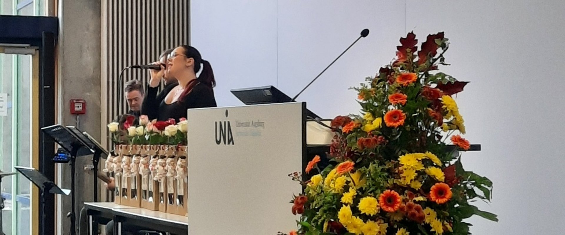 Absolventenfeier Rewi 2024. Sängerin. Im Vordergrund ein Blumenbouquet.