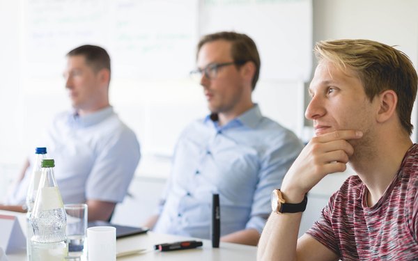 Drei Teilnehmer eines Seminars vor einem Flipchart