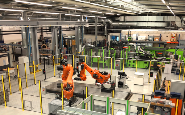 Blick von oben in die Halle 43 mit orangefarbenen Robotermaschinen in der Mitte, grünem Gestänge im Hintergrund.