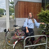 Hannah aus dem 3. Semester steht mit ihrem Fahrrad vor der Juristischen Fakultät