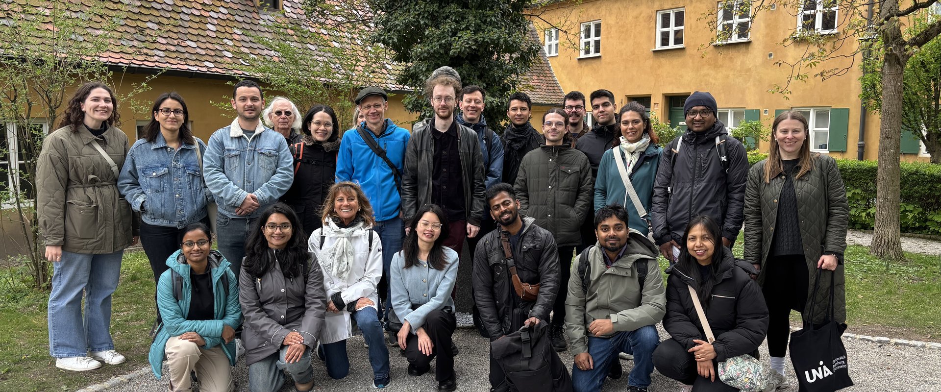 Gruppenbild von internationel Forschenden in kleinem Garten von der Sozialsiedlung Fuggerei in Augsburg