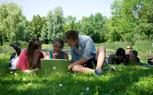 Studierende auf dem grünen Campus am See