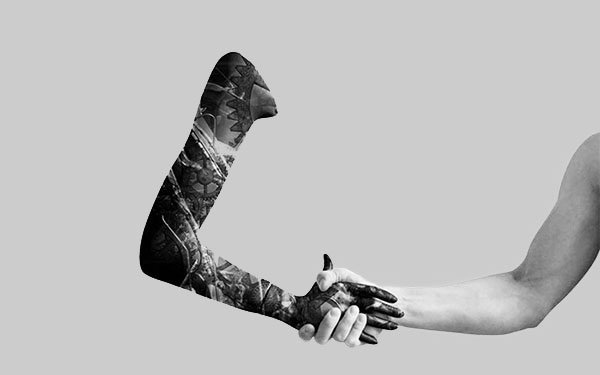zwei Arme, die sich die Hand geben, eine ist stark tätowiert