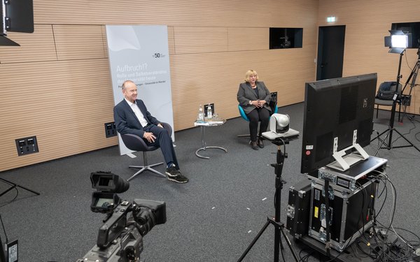 In einem Live-Studio diskutieren die Augsburger Universitätspräsidentin Prof. Dr. Sabine Doering-Manteuffel, ihr Hamburger Kollege Prof. Dr. Dieter Lenzen.