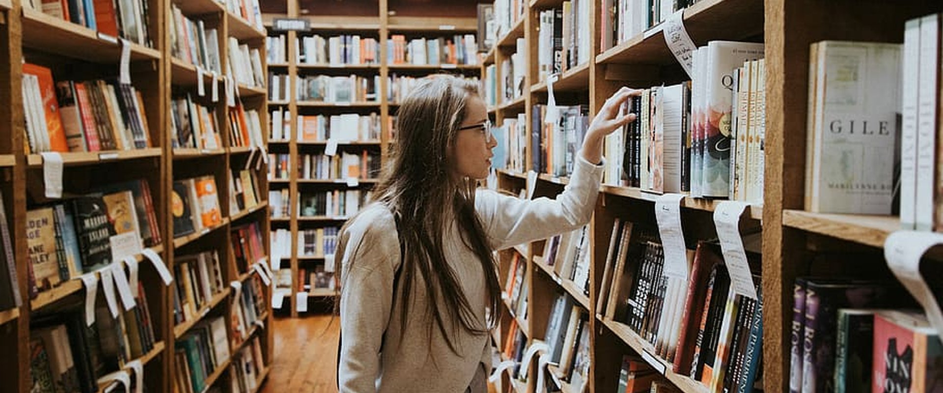 Junge Frau zwischen zwei Bücherreihen einer Bibliothek