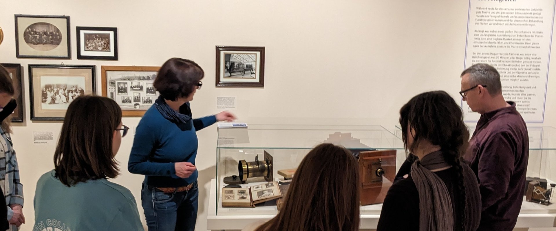 Einige Studierende stehen um die Kuratorin herum, die auf ein Museumsobjekt zeigt