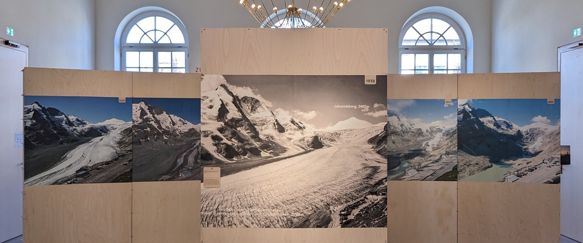 In einem Museumsraum stehen drei Holz e?nde auf die ein Bergpanorama gedruckt sind