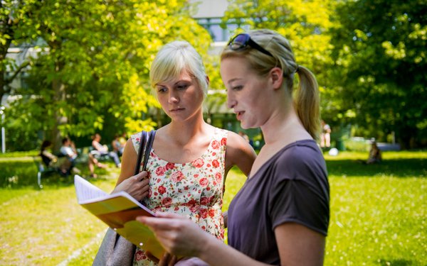 Zwei Studentinnen mit Buch im Innenhof