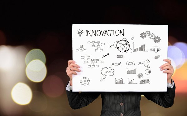 Frau hält Schild mit Mindmap Innovation hoch (Symbolbild)