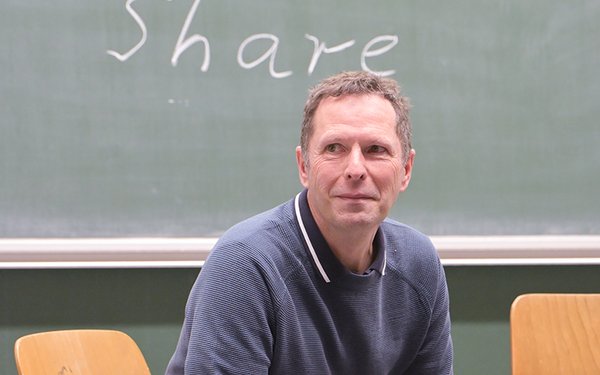 Zu sehen ist Prof. Dr. Andreas Hartinger, der vor einer Tafel sitzt, auf der "Think. Pair. Share." steht.