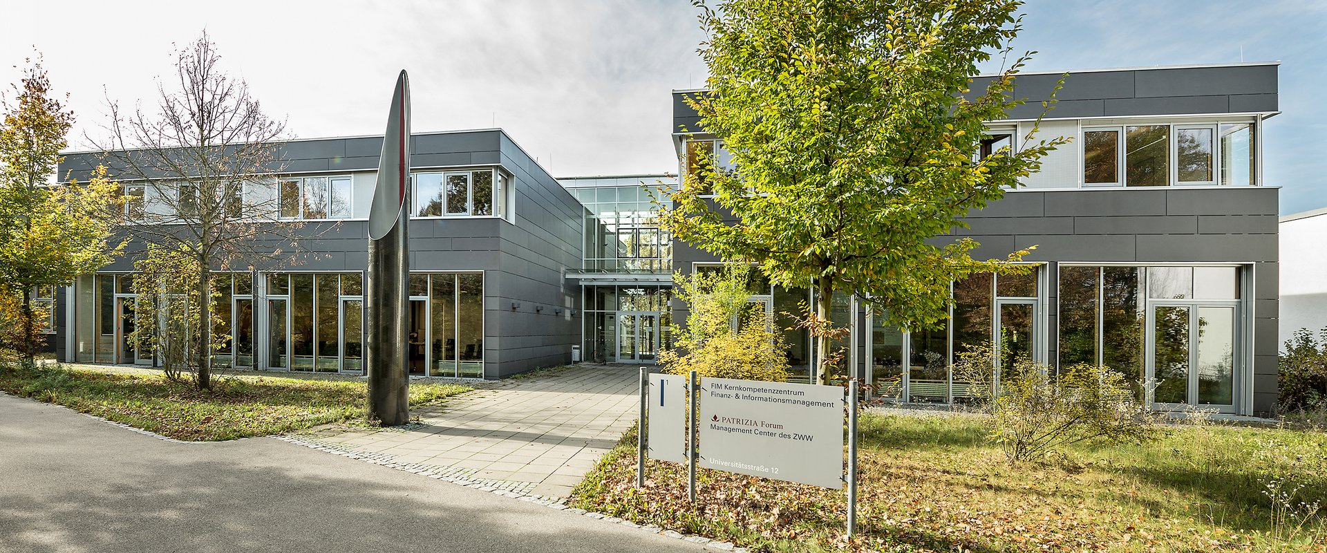 Auf dem Bild sieht man das Kunstwerk Pip vom Künstler Robert Kessler. Es stellt eine silberene Säule, die nach oben spitz zuläuft, dar.