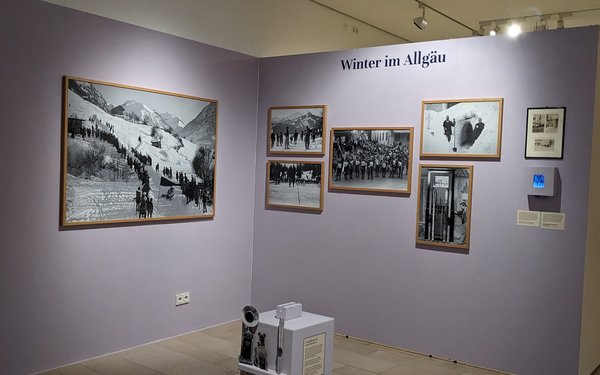Eine Museumswand in gr?ulichem flieder, daran h?ngen schwarz-wei? Bilder und die ?berschrift "Winter im Allg?u"