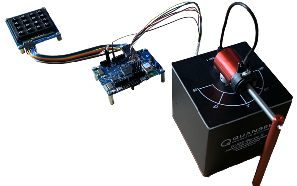 Auf dem Bild ist ein inverses Pendel (Quanser Qube 2) zu sehen. Er ist mit einem Microcontroller (STM32) verbunden. Der Microcontroller ist wiederum mit einer Button Matrix verbunden.