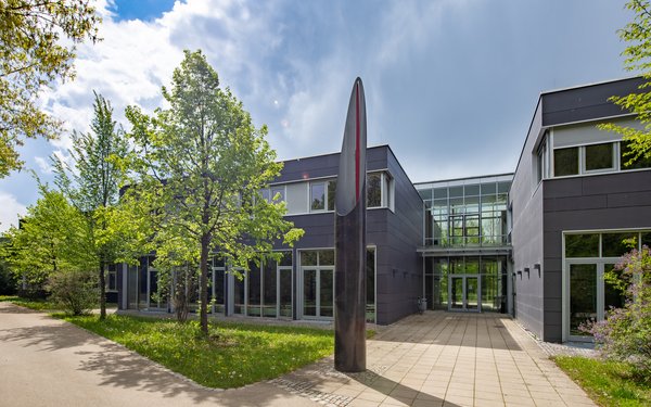 Gebäude mit Kunstwerk im grünen Campus