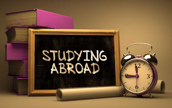 Bücher, Wekcer sowie Tafel mit Aufschrift "Study Abroad"