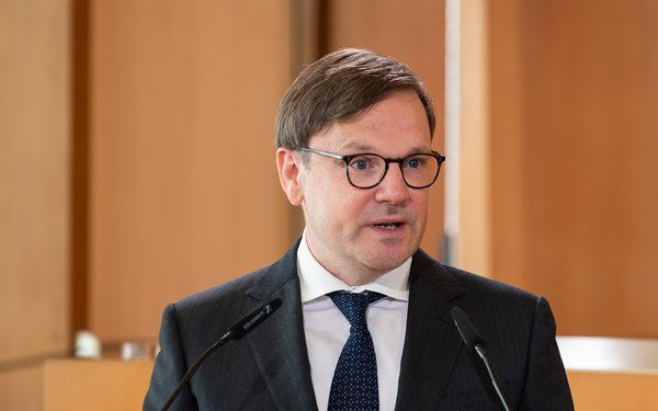 Prof. Dr. Ferdinand Wollenschläger an einem Rednerpult vor heller Holzvertäfelung.