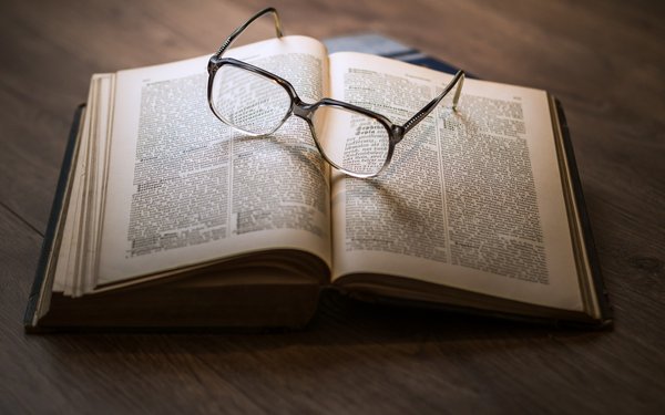 Buch aufgeschlagen, darauf liegt Brille