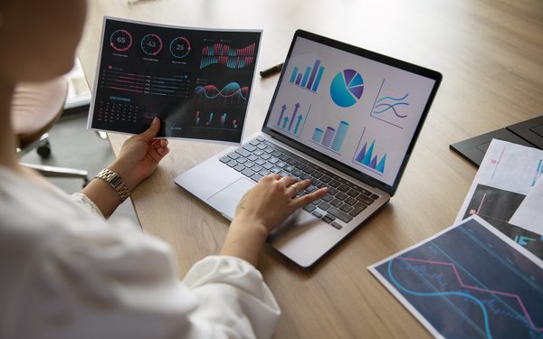 Eine Person arbeitet an einem Laptop mit verschiedenen Diagrammen.