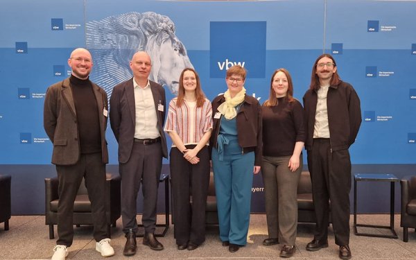 Das sechsk?pfige Team (drei M?nner und drei Frauen) steht vor blauem Hintergrund mit vbw-Logo und l?chelt in die Kamera