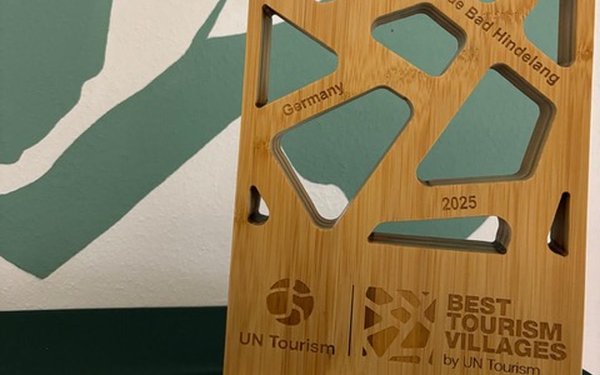 Preis für Best Tourism Village 2025 vor dem Logo von Bad Hindelang