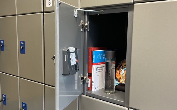 graues Schließfach mit geöffneter Tür, drinnen einige Arbeitsmaterialien