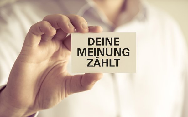 Eine Hand hält eine Karte auf der steht "Deine Meinung zählt"