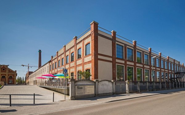 Das Alte Fabrikgebäude der Kammgarnspinnerei (Backstein Gebäude mit flachem Dach) in dem heute das tim Augsburg ist.
