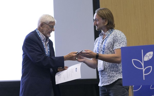 Erik De Corte übergibt Martin Daumiller den „Erik-De-Corte-Award“