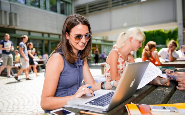 Studierende mit Laptop arbeiten vor der Alten Cafetè