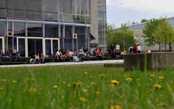 Studierende sitzen draußen vor der Bibliothek