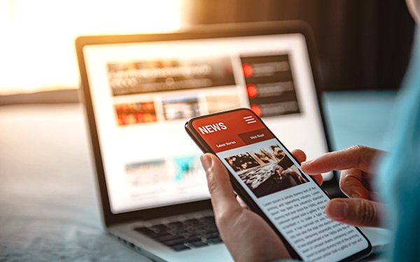 Smartphone und Laptop mit Nachrichten-Website