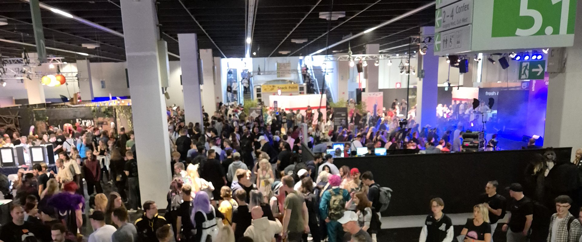 View from above into the exhibition hall. Many people are crowding the aisles.