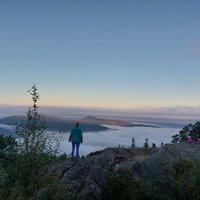Eine Person blickt auf wolkenverhangene Berggipfel