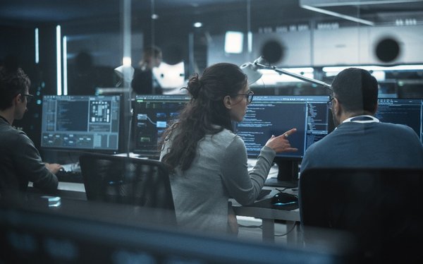 Programmierer vor PCs sitzend und über Computercode diskutierend