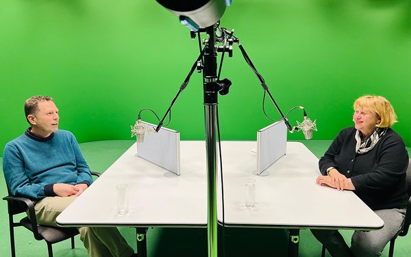 Universitätspräsidentin Prof. Dr. Sabine Doering-Manteuffel spricht im Zuge des Podcasts vor einem Greenscreen mit Grundschulpädagoge und -didaktiker Prof. Dr. Andreas Hartinger