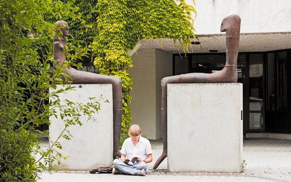Student sitzt  vor einem der Kunstwerke auf dem Campus