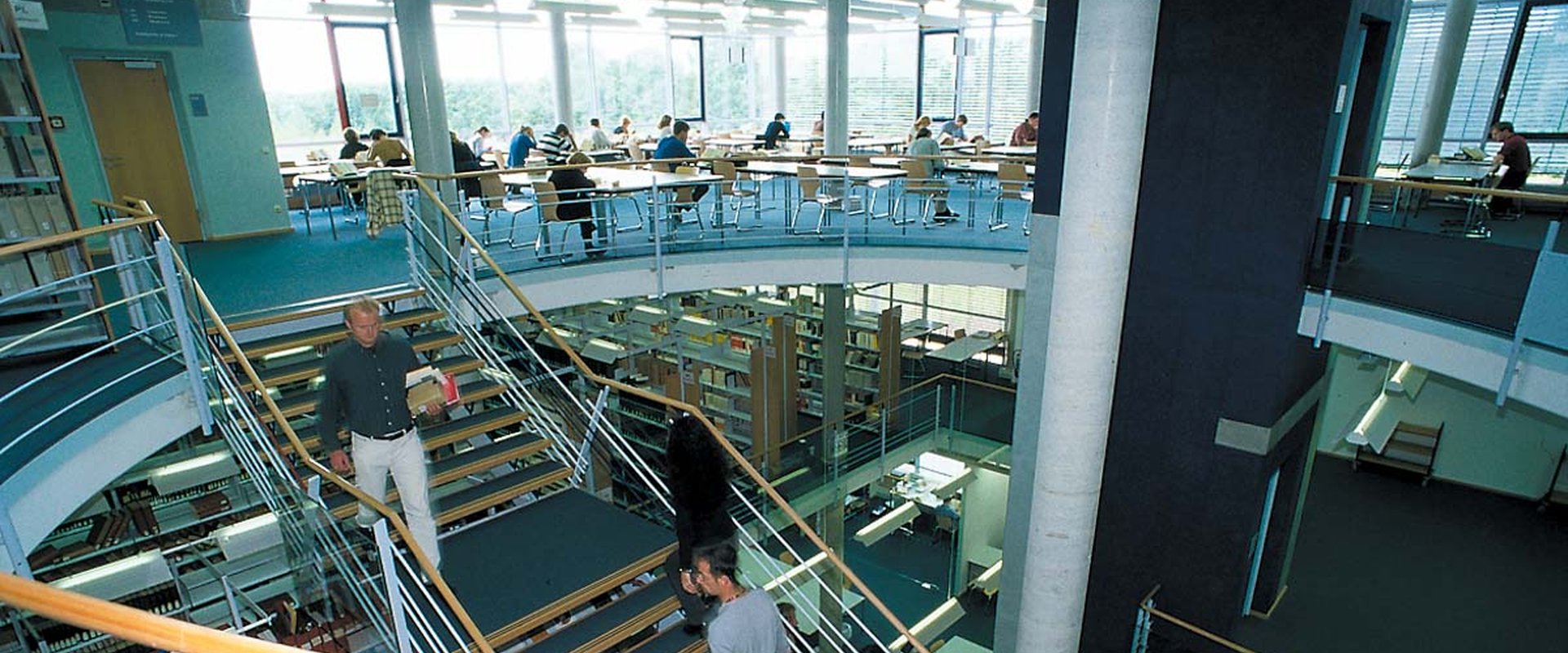 Blick in die Bibliothek mit offenem Treppenhaus im Mittelpunkt