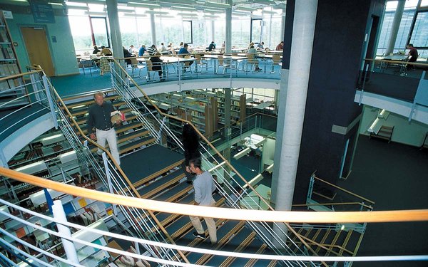 Blick in die Bibliothek mit offenem Treppenhaus im Mittelpunkt