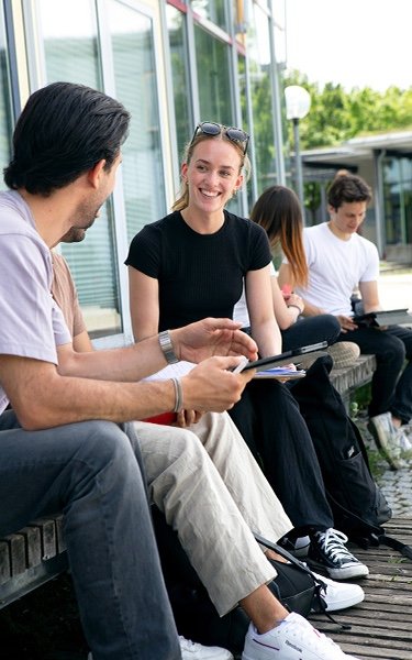 Studierende sitzen auf dem Campus und lernen im Freien, Gruppenarbeit, Studium, Austausch
